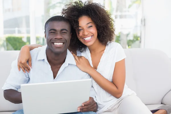 Attractive couple using laptop together on sofa — Stock Photo, Image