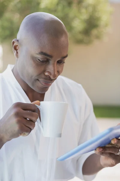 Handsome man in bathrobe using tablet at breakfast outside — Stock Photo, Image