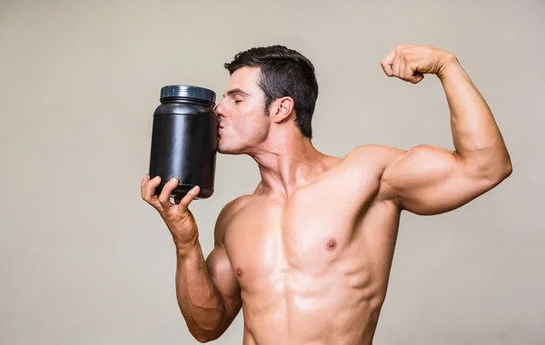 Muscular man kissing nutritional supplement — Stock Photo, Image
