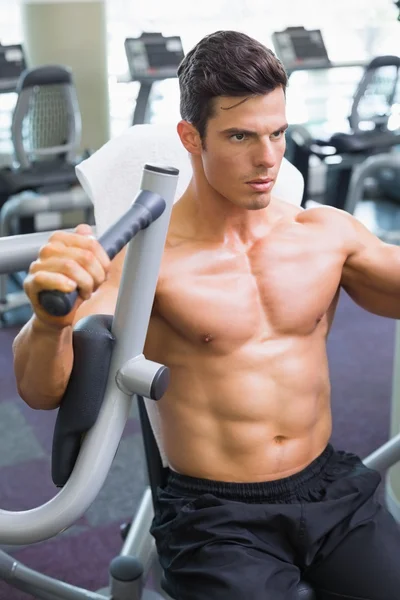 Gespierde man aan het werk op fitness machine op de sportschool — Stockfoto