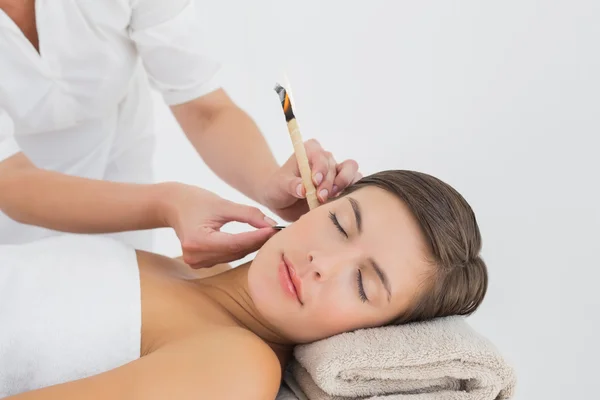Beautiful woman receiving ear candle treatment at spa center — Stock Photo, Image