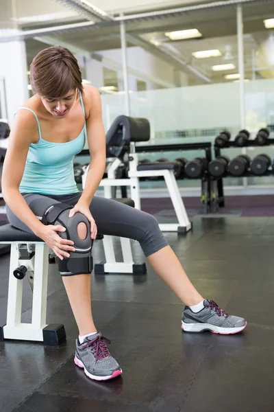 Fitte Brünette sitzt auf Bank mit verletztem Knie — Stockfoto