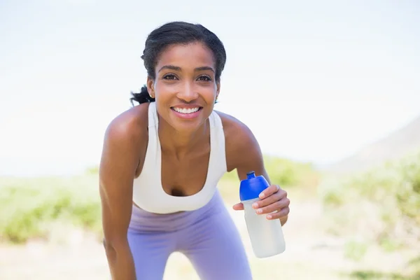 Fit woman holding sports bottle smiling at camera — Stock Photo, Image