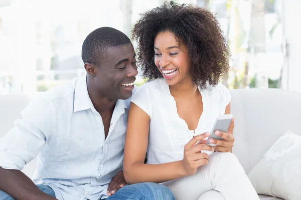 Attraktives Paar, das zusammen auf der Couch sitzt und aufs Smartphone schaut — Stockfoto