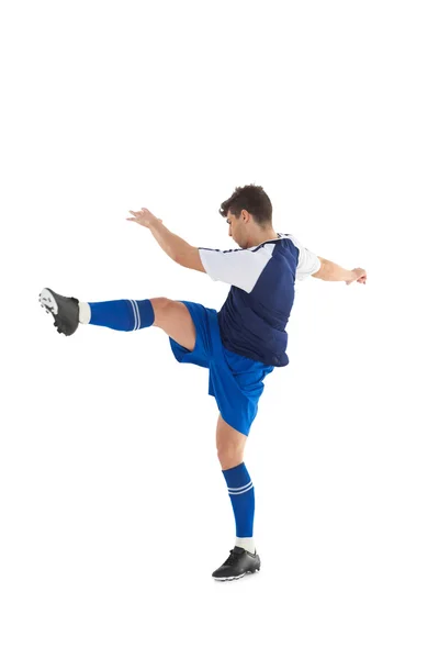 Футболист в синей майке пинается — стоковое фото