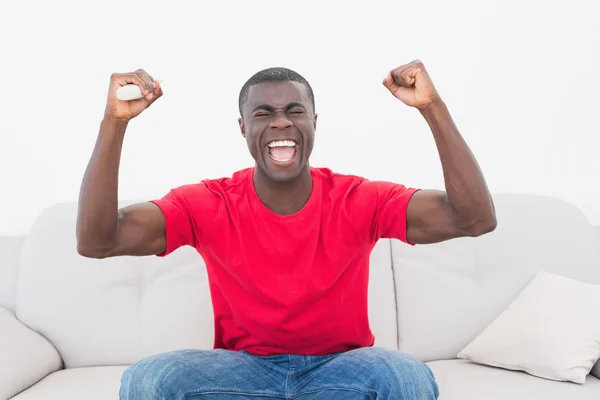 Jubelnder Fußballfan in Rot sitzt auf Couch — Stockfoto