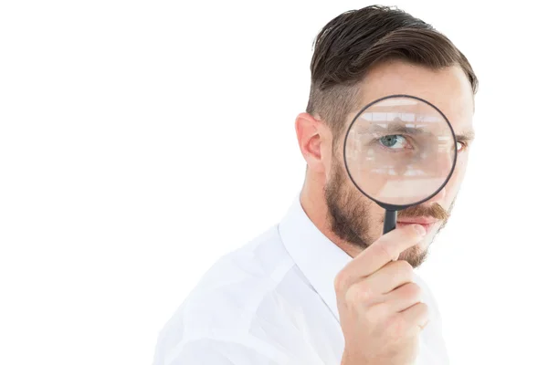 Geeky businessman looking through magnifying glass — Stock Photo, Image
