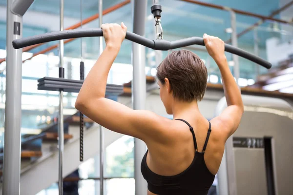 Fit brunette using weights machine for arms — Stock Photo, Image