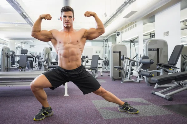 Hombre musculoso sin camisa flexionando los músculos en el gimnasio — Foto de Stock