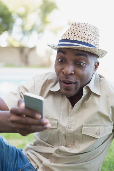 Smiling man relaxing in his garden texting on phone — Stock Photo, Image