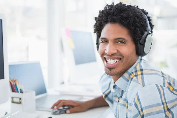 Young designer listening to music as he works — Stock Photo, Image