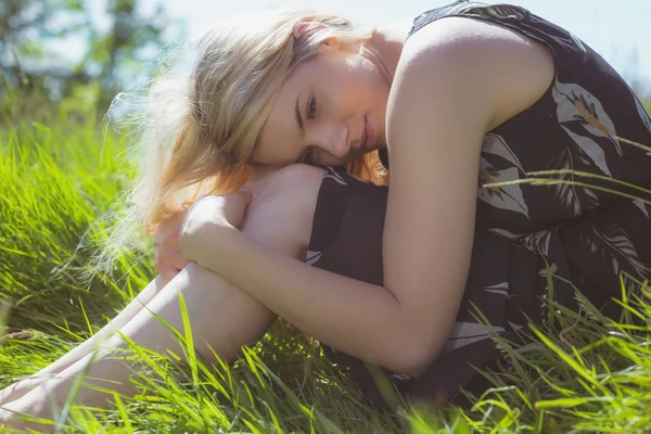 Jolie blonde en robe de soleil assise sur l'herbe — Photo