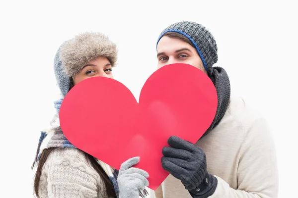 Attractive young couple in warm clothes holding red heart — Stock Photo, Image