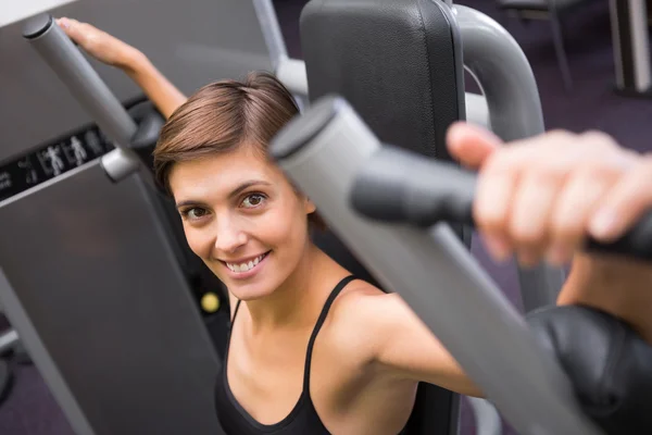 Morena feliz usando la máquina de pesos para los brazos — Foto de Stock