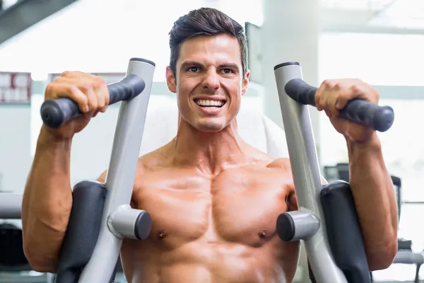 Uomo muscolare che lavora sulla macchina fitness in palestra — Foto Stock