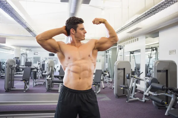 Shirtless gespierde man buigen spieren in de sportschool — Stockfoto