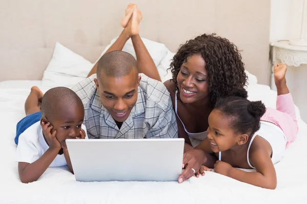 Met behulp van laptop samen op bed en gelukkige familie — Stockfoto