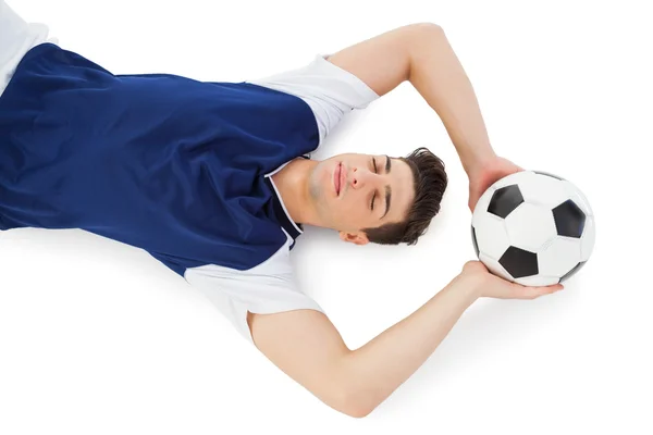 Jogador de futebol deitado no chão com bola — Fotografia de Stock