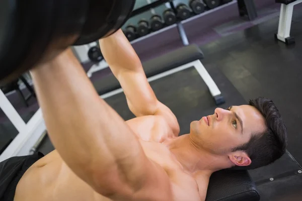 Uomo muscolare che si esercita con i manubri in palestra — Foto Stock