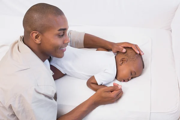 Adorable baby boy sleeping while being watched by father Stock Image