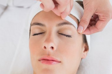 Hand waxing beautiful woman's eyebrow clipart