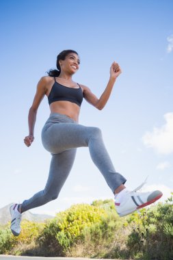 Fit woman running along the open road clipart