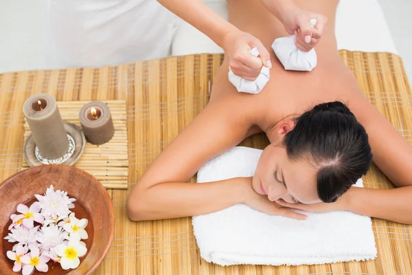 Friedliche Brünette genießt eine Kräuterkompresse Massage — Stockfoto