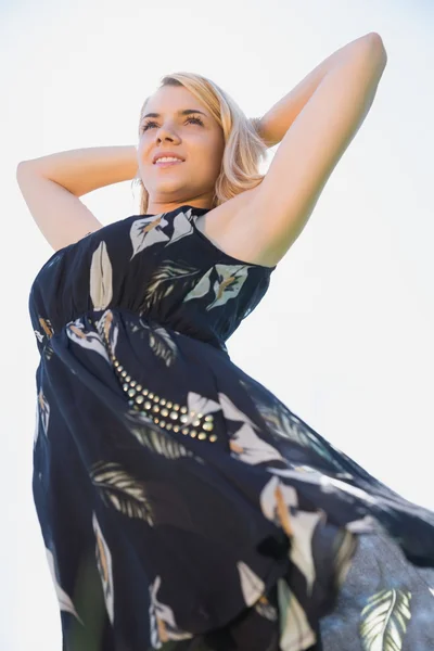 Hübsche Blondine in Sundress mit Armen hinter dem Kopf stehend — Stockfoto