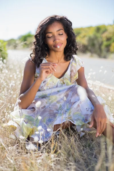 Šťastná hezká žena sedící na trávě v květinové šaty — Stock fotografie