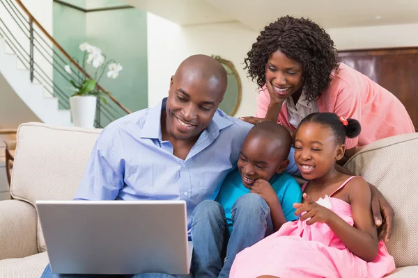 Família feliz relaxante no sofá usando laptop — Fotografia de Stock