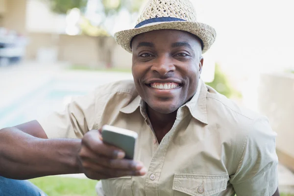 Uomo sorridente che si rilassa nel suo giardino messaggiando al telefono — Foto Stock