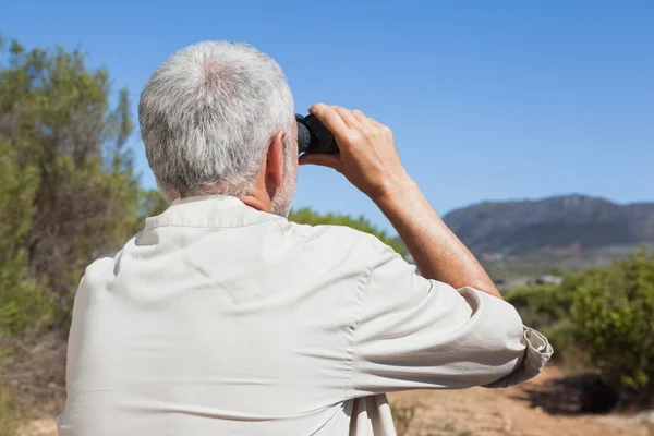 Hiker taking a break on country trail looking through binoculars — Stock Photo, Image