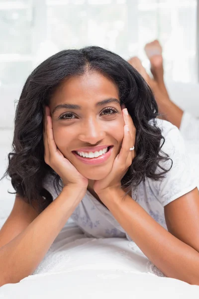 Mujer bonita sonriendo a la cámara acostada en la cama —  Fotos de Stock