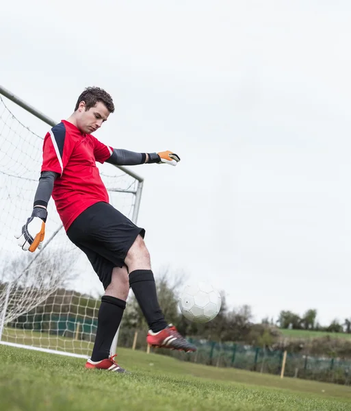 Keeper in het rood schoppen de bal uit de buurt van doel — Stockfoto