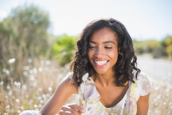 Happy pretty woman sitting on the grass in floral dress — Stock Photo, Image