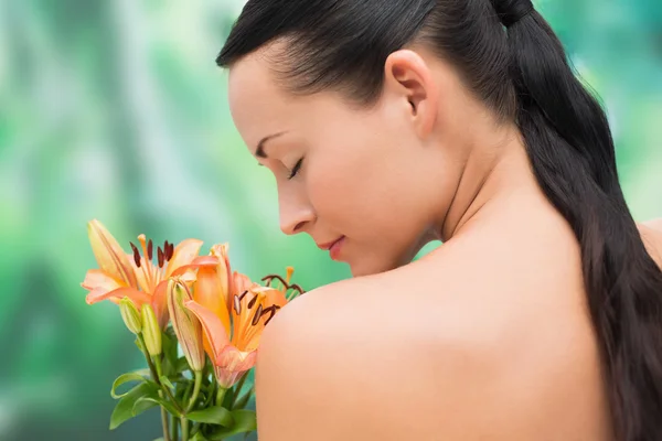 Beautiful nude brunette smelling bunch of lilies — Stock Photo, Image