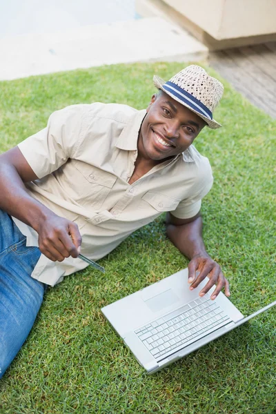 Bonito homem relaxante em seu jardim usando laptop para fazer compras — Fotografia de Stock