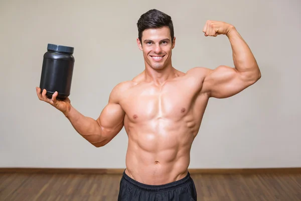 Gespierde man poseren met voedingssupplement in gym — Stockfoto