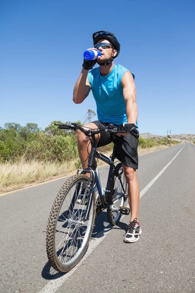 Knappe wielrenner nemen van een pauze op zijn fiets drinkwater — Stockfoto