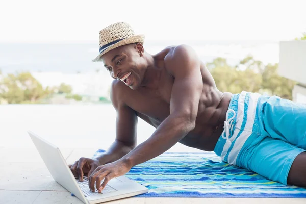 Bello uomo senza camicia che utilizza il computer portatile a bordo piscina — Foto Stock