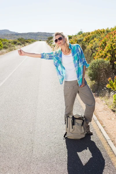 Blonde hitch hiking op landelijke weg — Stockfoto