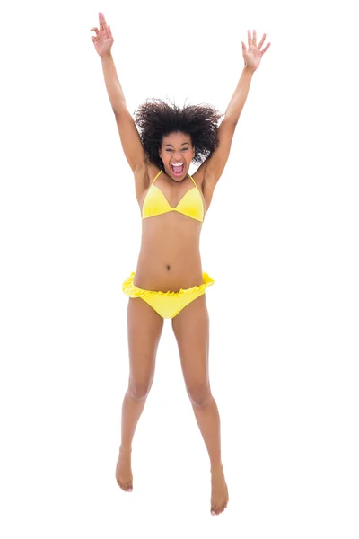 Fit girl in yellow bikini jumping and smiling at camera — Stock Photo, Image