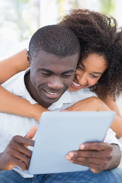 Attractive couple sitting on couch together looking at tablet — Stock Photo, Image