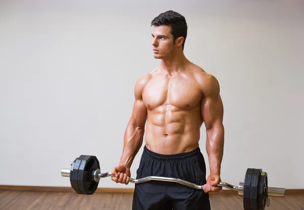 Shirtless muscular man lifting barbell in gym — Stock Photo, Image