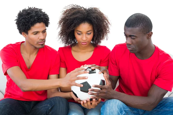 Aficionados al fútbol en rojo sosteniendo la pelota juntos — Foto de Stock