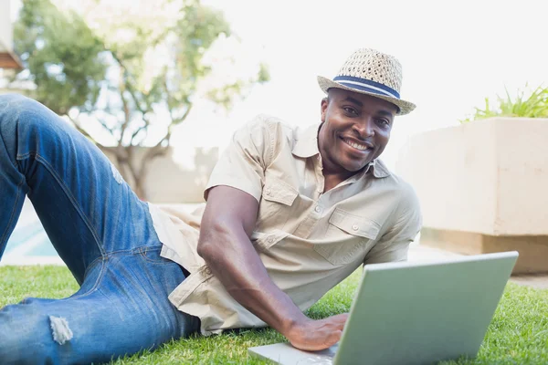 Красивый мужчина расслабляется в саду с помощью ноутбука — стоковое фото