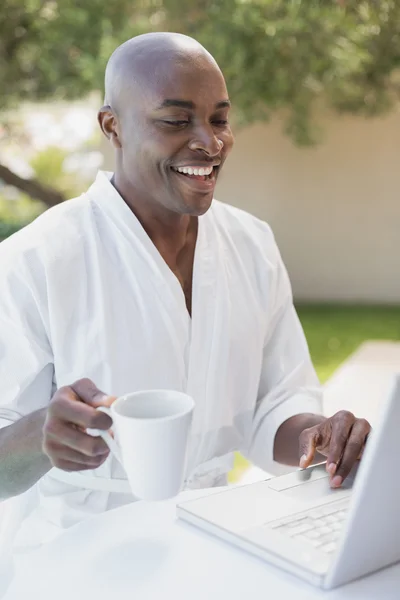 Hombre guapo en albornoz usando portátil en el desayuno al aire libre —  Fotos de Stock