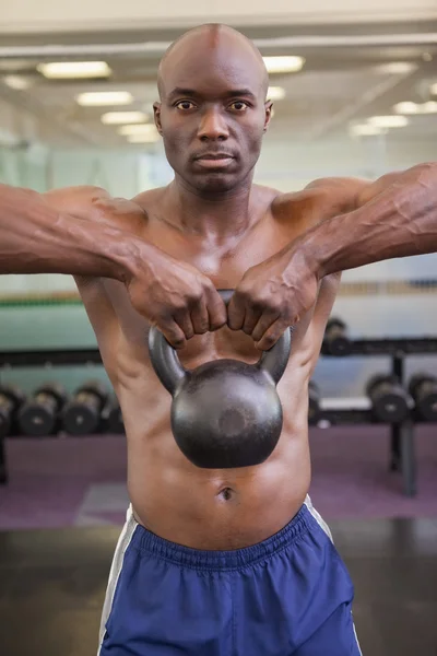 Muscular man lifting kettle bell in gym — Stock Photo, Image