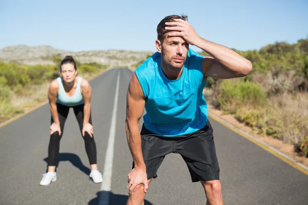 Fit couple jogging on the open road together — Stock Photo, Image