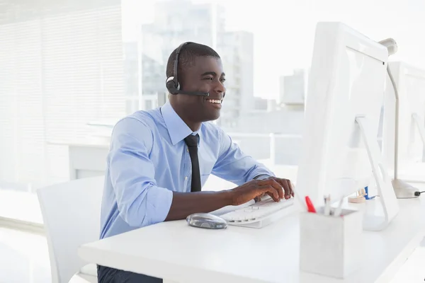 Feliz hombre de negocios trabajando en su escritorio con auriculares —  Fotos de Stock